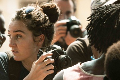 Une foule de personne, dont une femme avec un appareil photo qui regarde vers la droite