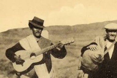 4 hommes marchent. L'un porte une guitare, les 3 autres des sacs. C'est une photographie assez ancienne des années 40.