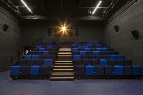 Un amphithéâtre aux sièges bleus et noirs