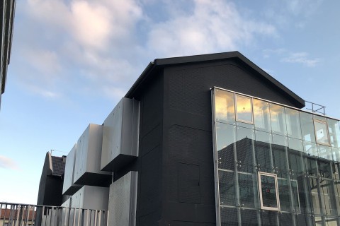 La façade arrière du Lavoir, peinte en noir avec excroissances alu et verre